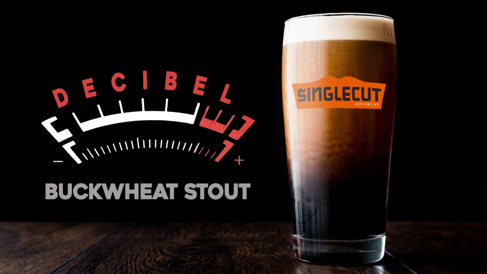 pint glass filled with stout beer and the name decibel buckwheat stout